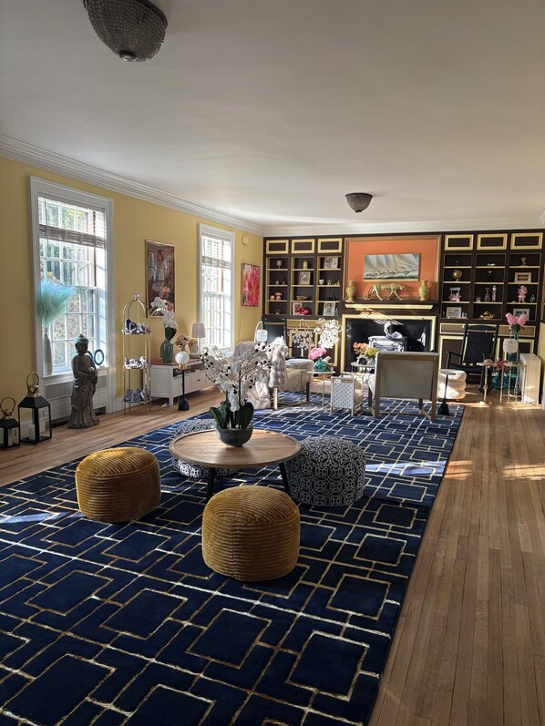 A well-lit living room with a patterned rug, wooden flooring, and a fireplace.