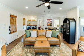 A living room with a sofa, ottoman, and a ceiling fan.
