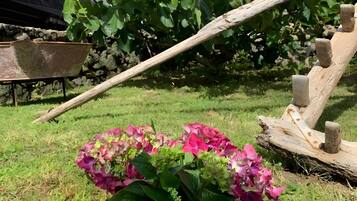 Ein Garten mit Blumenbeet, einer Holzschaukel und einem Schubkarren.