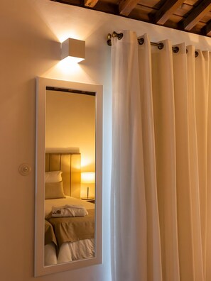 A mirror with a reflection of a bed, a nightstand, and a lamp.