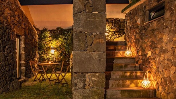A stone staircase leading to a covered outdoor area with a table and chairs, and two lantern-style lights.