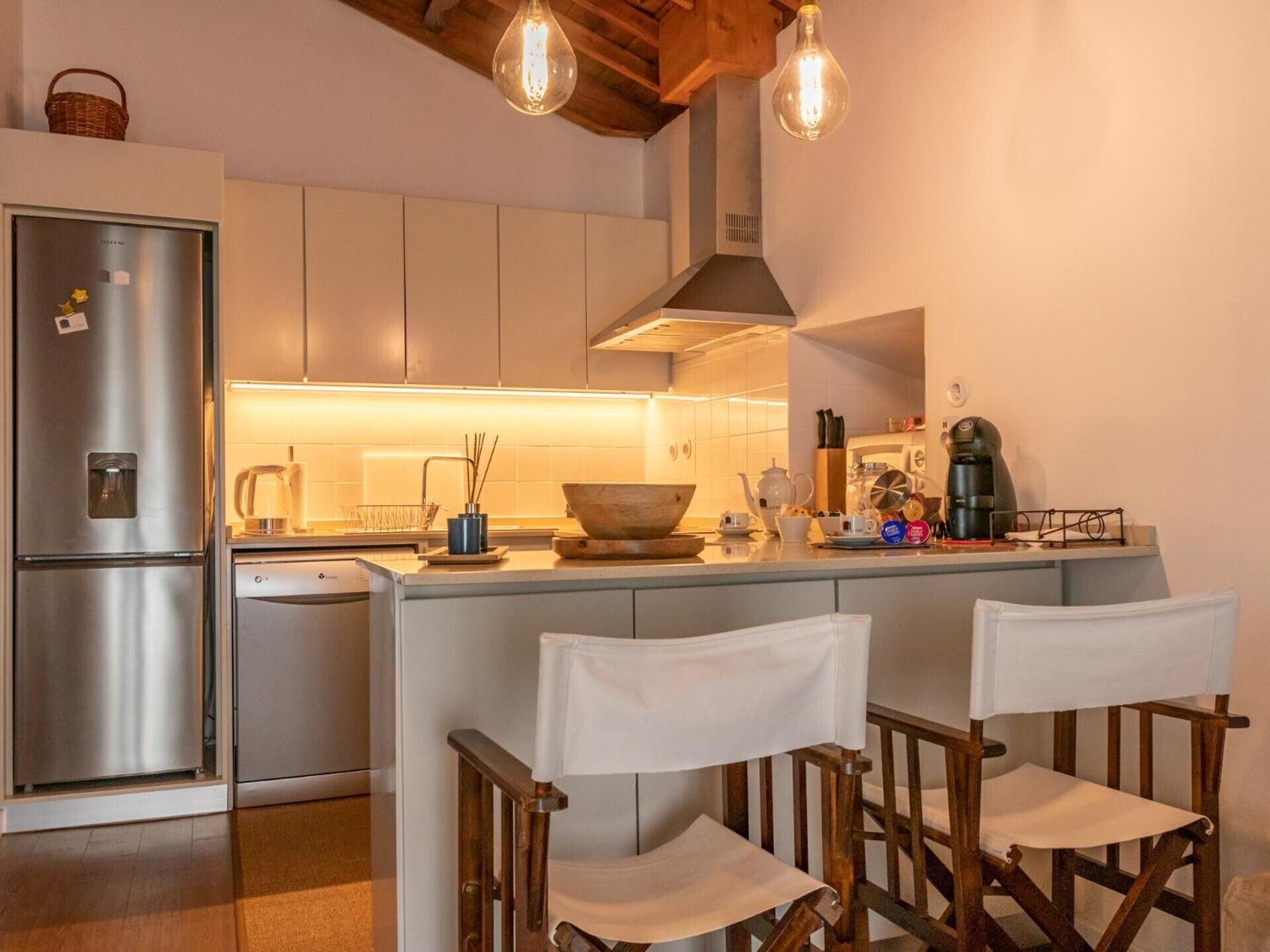 Cozinha moderna com eletrodomésticos de aço inoxidável, uma ilha central com banquetas e iluminação pendente.