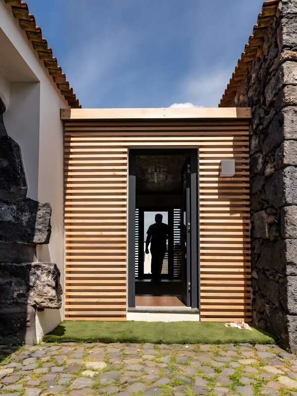 Una entrada moderna a un edificio con una puerta de madera y un muro de piedra.