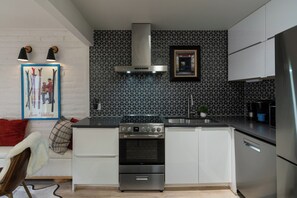 Une cuisine compacte équipée d’une cuisinière à gaz, d’un four et d’appareils électroménagers en acier inoxydable.