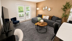 A living room with a sofa, a coffee table, a TV, and a plant.