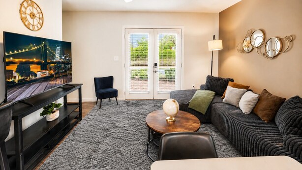 A living room with a flat-screen TV, a sofa, a coffee table, and a chair.