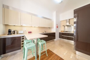A modern kitchen with a central island, bar stools, and a stainless steel range hood. - GuestReady - Sleek stay near Pink Street (Lisbon)