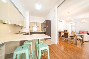 A modern kitchen with a central island, bar stools, and a dining area with a table and chairs. - GuestReady - Sleek stay near Pink Street (Lisbon)
