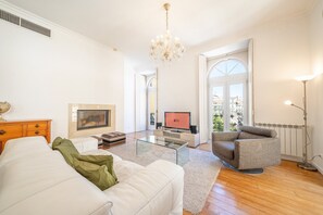 A modern living room with a fireplace, a television, a sofa, a coffee table, and a chandelier. - GuestReady - Sleek stay near Pink Street (Lisbon)