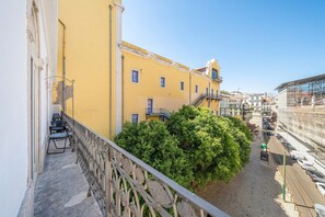 A yellow building with a balcony, a staircase, and a view of a street with cars and a construction site. - GuestReady - Sleek stay near Pink Street (Lisbon)