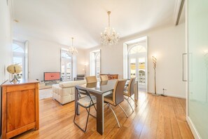 A spacious living area with a dining table, chairs, and a chandelier. - GuestReady - Sleek stay near Pink Street (Lisbon)