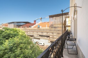 A balcony with a view of a construction site, a white van, and a building with scaffolding. - GuestReady - Sleek stay near Pink Street (Lisbon)