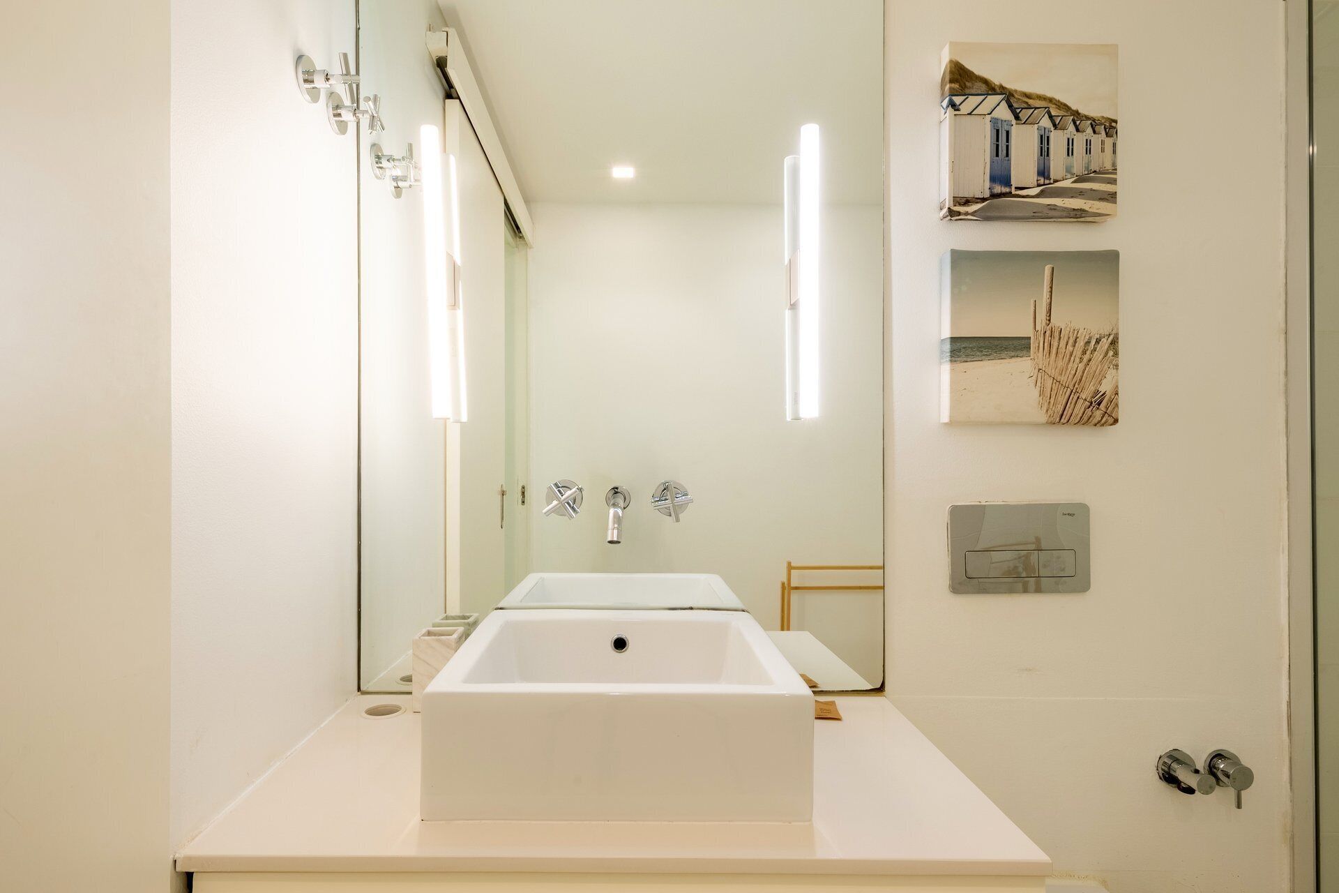 Ein modernes Badezimmer mit einem großen, rechteckigen Waschbecken, einem Spiegel und einem Handtuchhalter an der Wand.
