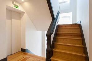 A staircase with wooden steps and black handrails, leading to an upper floor. - GuestReady - Wonderful flat near the Pink Street (Lisbon)