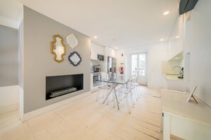 A modern kitchen with a glass dining table, a fireplace, and a kitchen island. - GuestReady - Wonderful flat near the Pink Street (Lisbon)