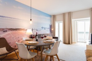 Ein Essbereich mit Tisch für vier Personen, einer Stadtansicht-Mural an der Wand und einem Balkon mit Vorhängen.