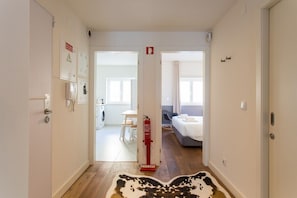 A hallway with a fire extinguisher, a coat rack, and a door leading to a room with a bed and a window. - GuestReady - Stylish stay near the National Museum (Lisbon)