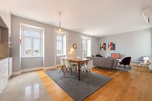 Een moderne woonkamer met een eetgedeelte, grote ramen en uitzicht op de stad.