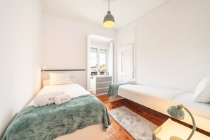 Quarto com duas camas, uma janela e porta para o exterior.