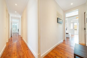 A hallway with wooden flooring, white walls, and a door leading to another room. - GuestReady - Stunning flat in Principe Real (Lisbon)