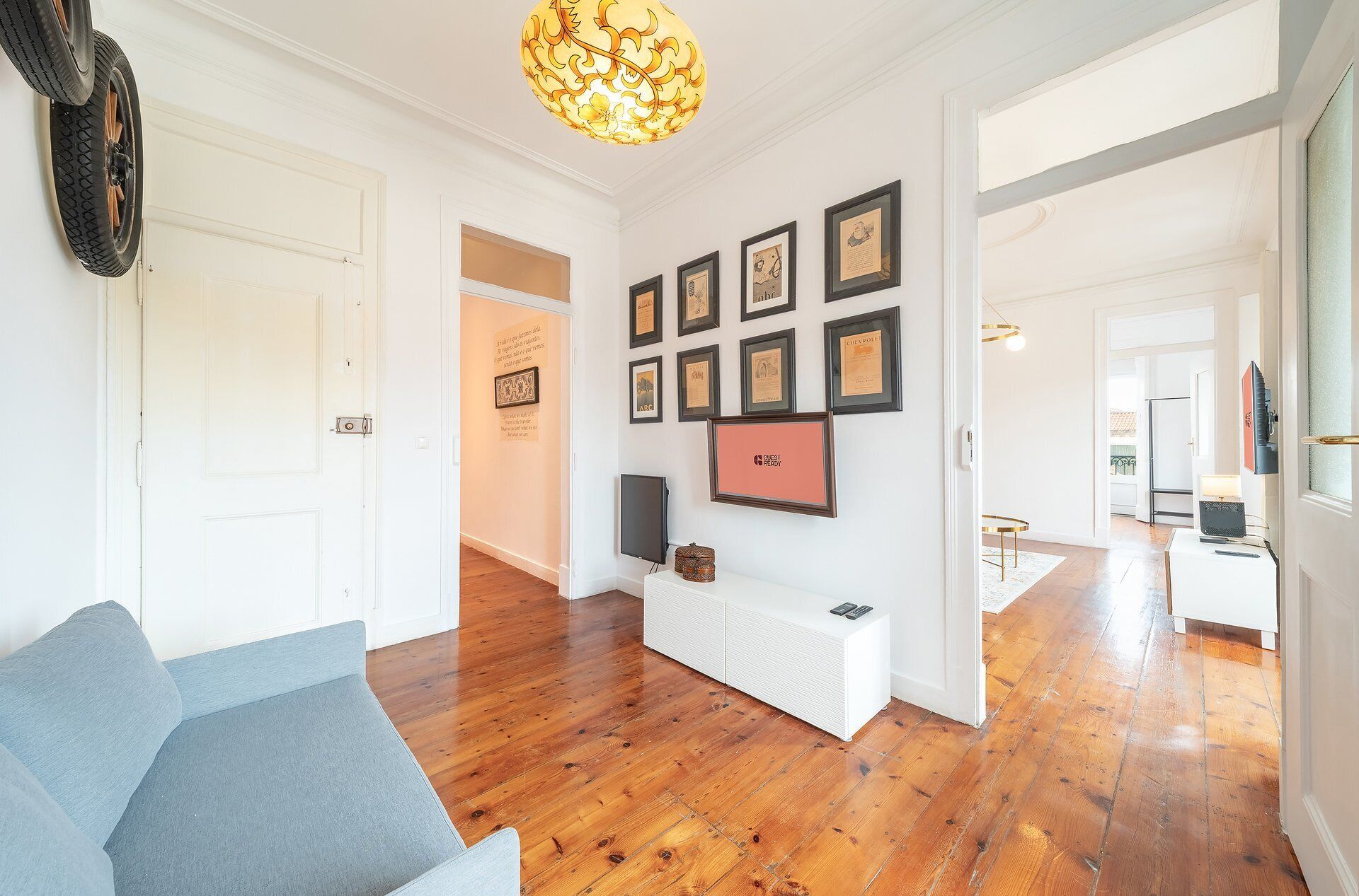 Un'ampia zona giorno con pavimento in legno, una panca bianca e un muro decorato con cornici e certificati.