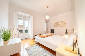 Quarto com cama, mesa de cabeceira, abajur e uma parede com uma citação.