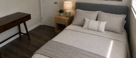A bedroom with a bed, bedside table, lamp, and a ceiling fan.