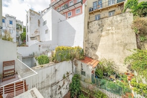Eine schmale Stadtstraße, gesäumt von Gebäuden mit Balkonen und begrünten Fassaden.