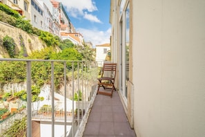 A narrow balcony with a chair, overlooking a cityscape with buildings and greenery. - GuestReady - Gorgeous stay near Time Out Market (Lisbon)