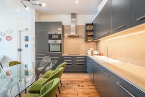 A modern kitchen with grey cabinets, a built-in oven, and a wooden floor. - GuestReady - Gorgeous stay near Time Out Market (Lisbon)
