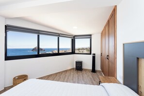 Ein Schlafzimmer mit großem Fenster, einem Bett, einem Kleiderschrank und einem Heizkörper.