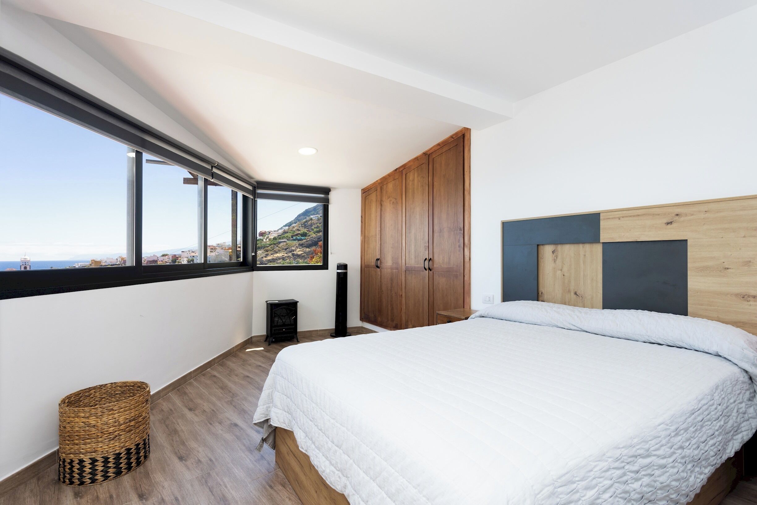 Une chambre avec un grand lit, une armoire en bois et une vue sur la mer.