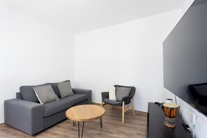 A modern living room with a grey sofa, a round wooden coffee table, a black armchair, and a drum set. - TenoHomes Lava and Atlantic Views Garachico (Garachico)