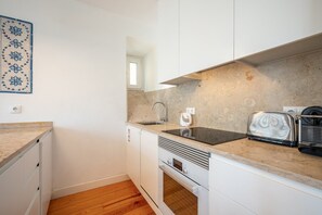 A compact kitchen with white cabinets, a built-in oven, a sink, and a toaster. - GuestReady - Chic flat near Lisbon Cathedral (Lisbon)