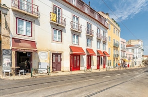 Eine Straße mit Gebäuden, einige mit roten Markisen und Balkonen.
