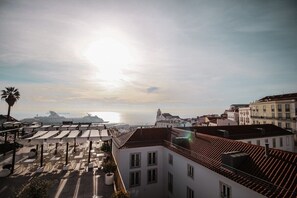 A coastal cityscape with buildings, a palm tree, and a cruise ship in the distance. - GuestReady - Chic flat near Lisbon Cathedral (Lisbon)