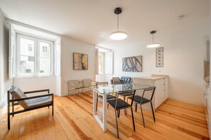 A modern kitchen with a glass dining table, wooden flooring, and pendant lighting. - GuestReady - Chic flat near Lisbon Cathedral (Lisbon)