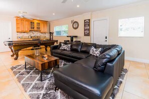 A living room with a sectional sofa, a coffee table, and a pool table. - Tropical 5BR Retreat ! Pool, Bar, Games & Nature (Sunrise)