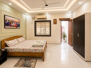 A bedroom with a bed, a ceiling fan, an air conditioning unit, a window with blinds, a door, and a potted plant. - HomeStay Near NTPC, Block Road, SDO Office Kahalgaon (Kahalgaon, Bhagalpur)