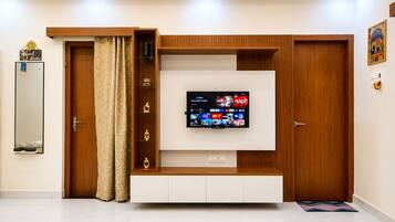 A modern living room with a flat-screen TV mounted on a wooden wall unit, a door with a mirror, and a decorative sign.