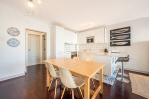 Eine moderne Küche mit weißen Schränken, einem Holztisch und einer Bar.