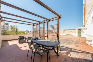 An outdoor patio with a table and chairs, a wooden pergola, and a view of the cityscape. - GuestReady - Stylish haven in Lisbon (Lisbon)