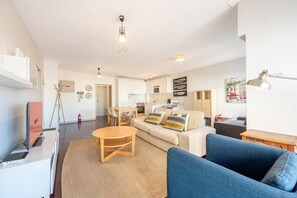 A modern living room with a sofa, a coffee table, and a dining area with chairs. - GuestReady - Stylish haven in Lisbon (Lisbon)