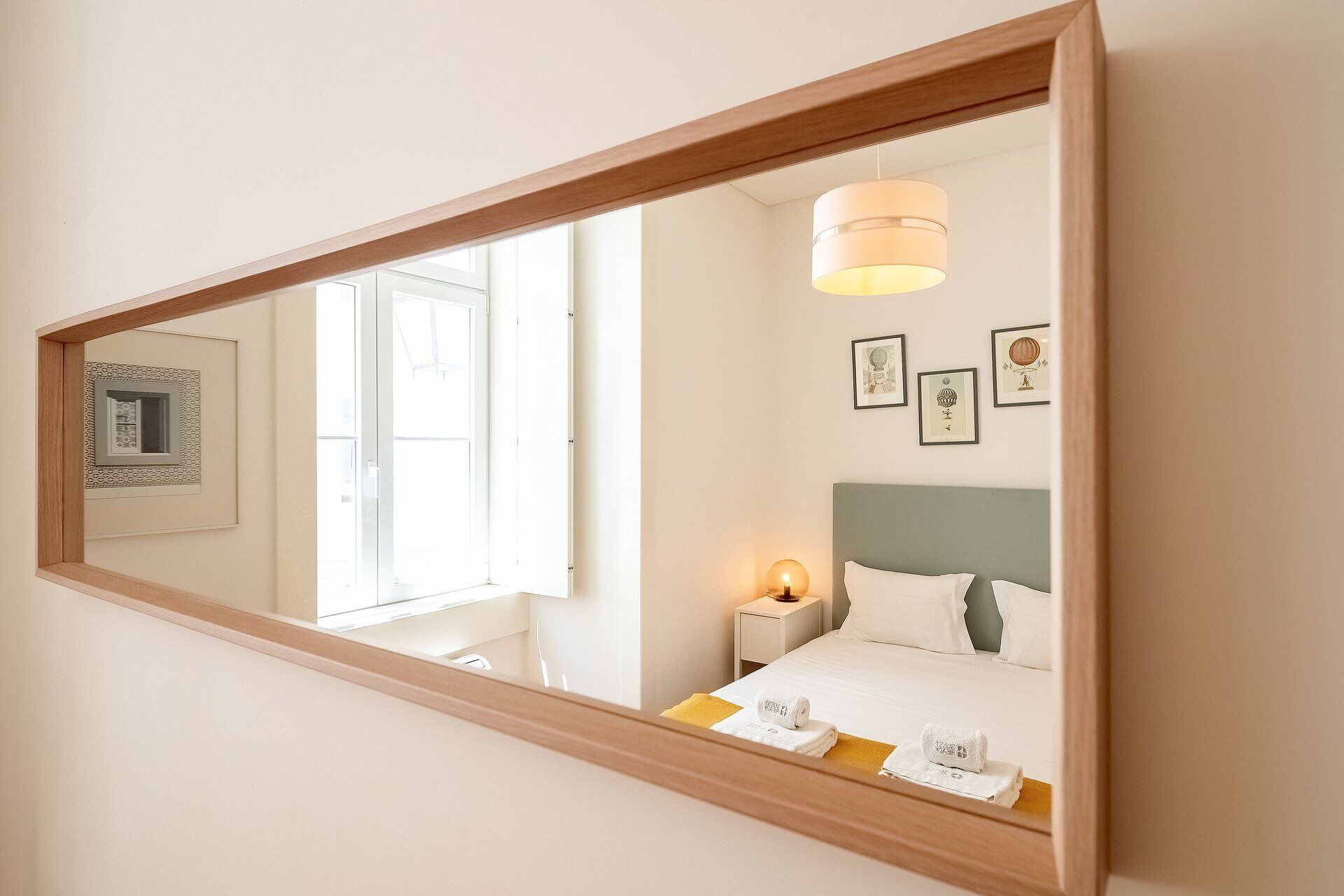 Ein Hotelzimmer mit einem großen Spiegel, einem Bett mit weißer Bettwäsche, einem Nachttisch mit einer Lampe und gerahmten Bildern an der Wand.