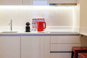 Eine moderne Küche mit integrierter Kaffeemaschine, einer roten Tasse und einem kompakten Kühlschrank.