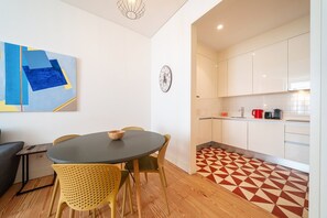 A modern kitchen with white cabinets, a red coffee pot, and a vintage camera. - GuestReady - Modern home near Rua Augusta (Lisbon)