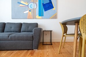 Ein modernes Wohnzimmer mit einem grauen Sofa, einem kleinen Beistelltisch und einem gelben Sessel.