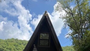 A wooden cabin with a triangular roof, a front door, and a small porch.