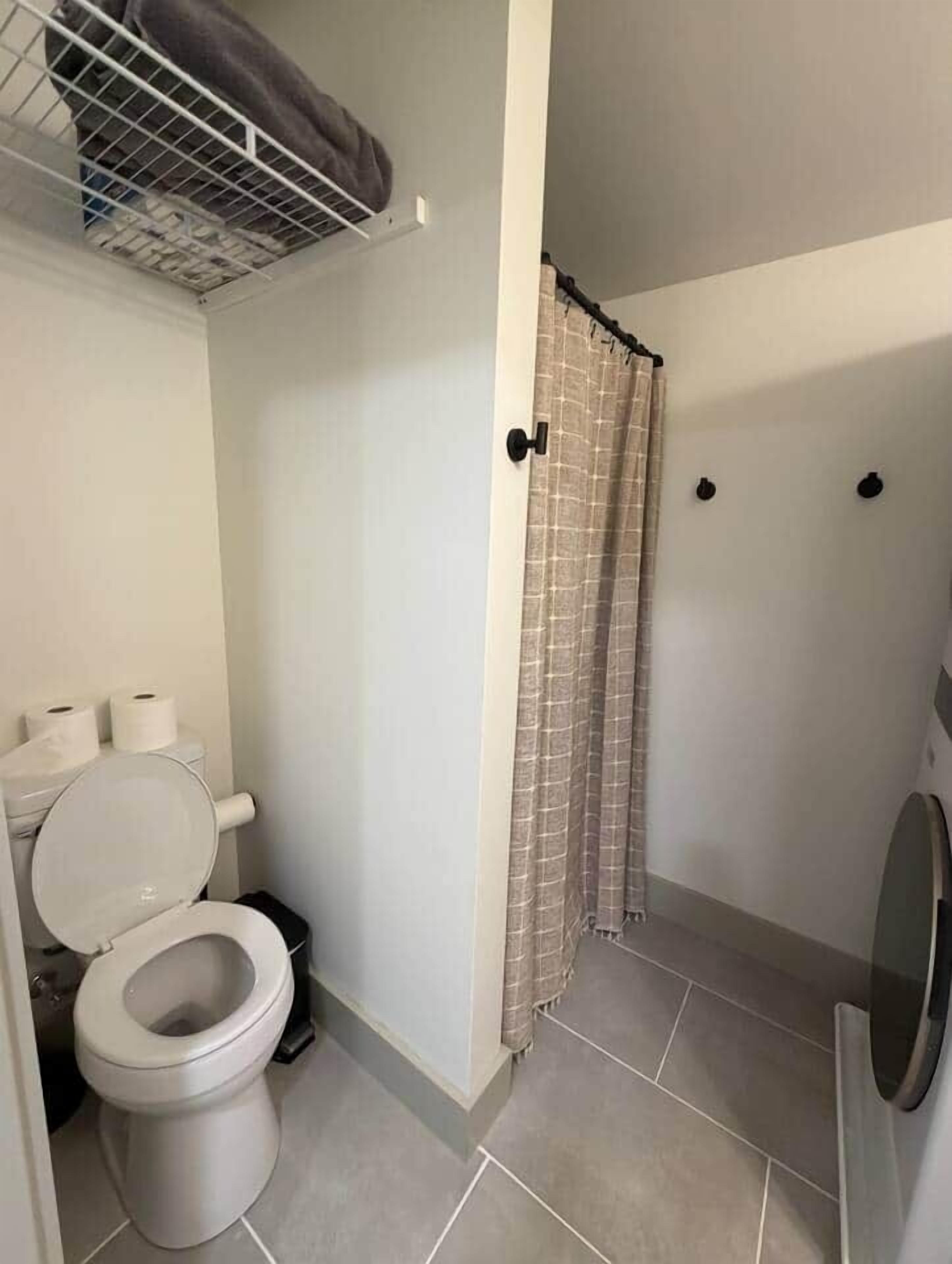 A bathroom with a toilet, a shower curtain, and a towel rack.