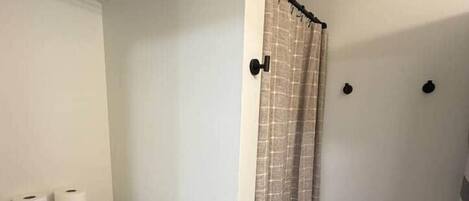 A bathroom with a toilet, a shower curtain, and a towel rack.